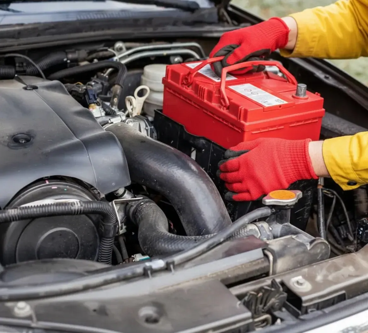 Red-gloved hands setting a red battery in place
