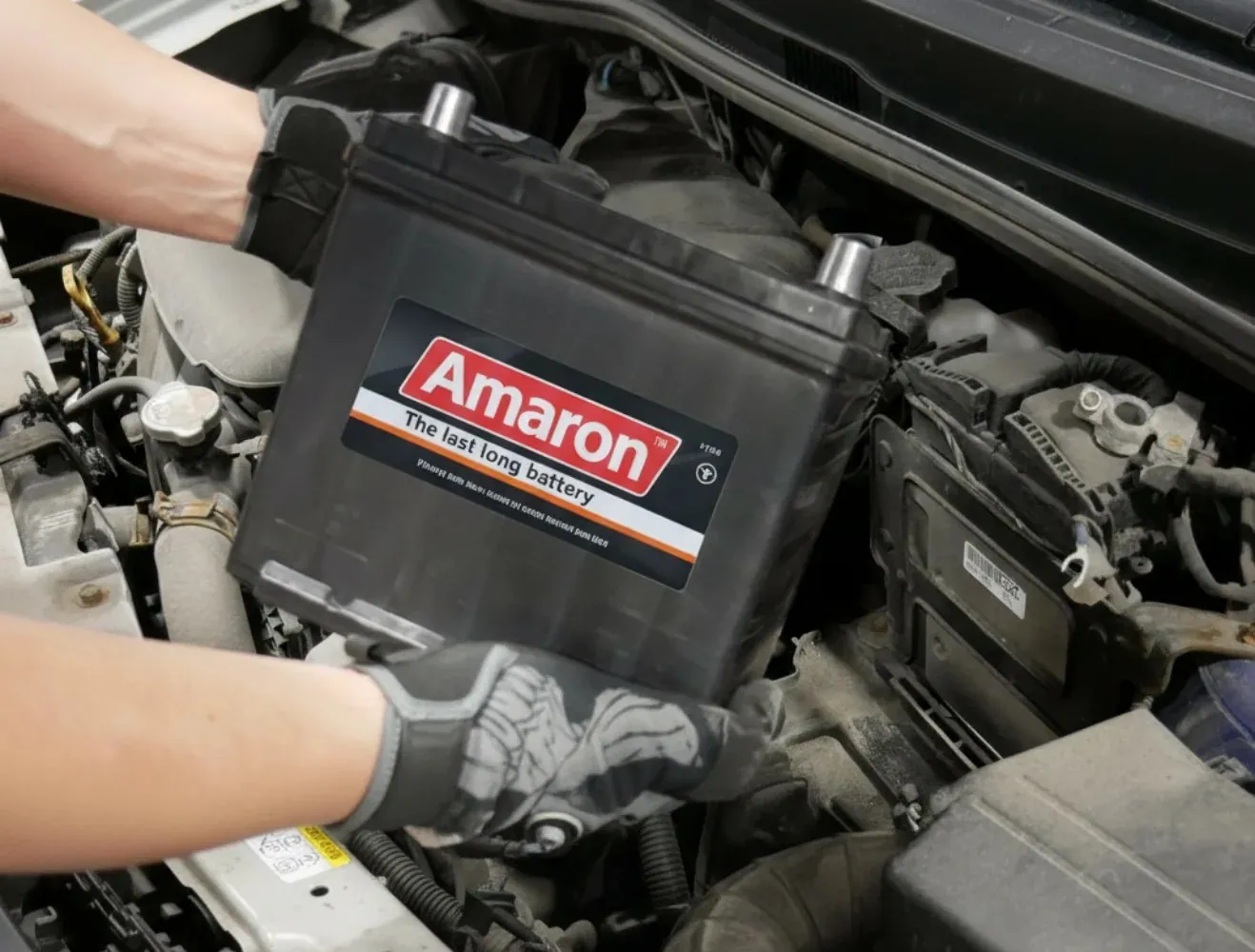 Gloved hands carrying an Amaron battery