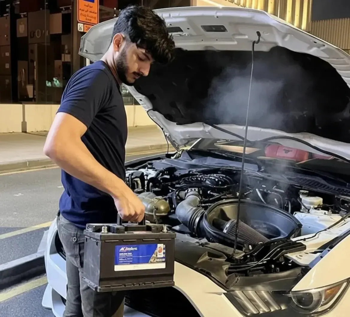 Careful hands on every job Technician carrying a battery to a steaming engine