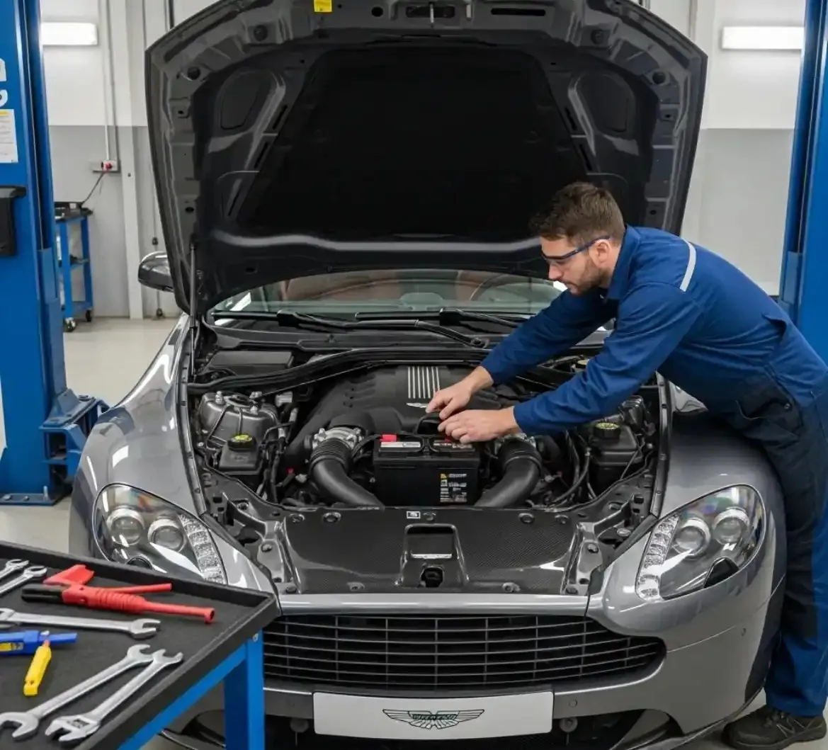 The Aston Martin and its battery Technician reaching into the engine bay of a grey Aston Martin