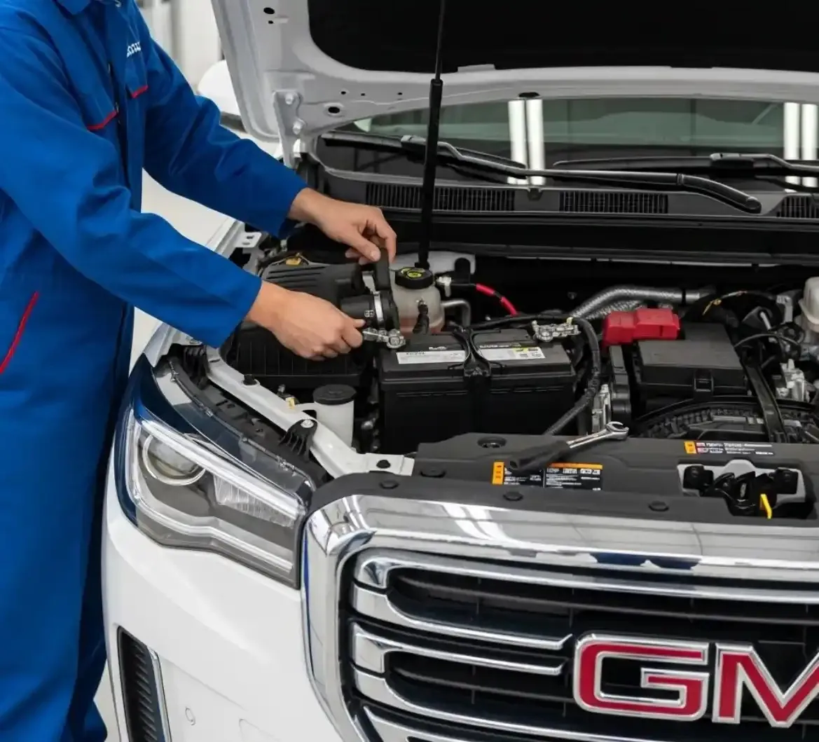 Testing before anything is replaced Technician in blue overalls working on a white GMC's battery